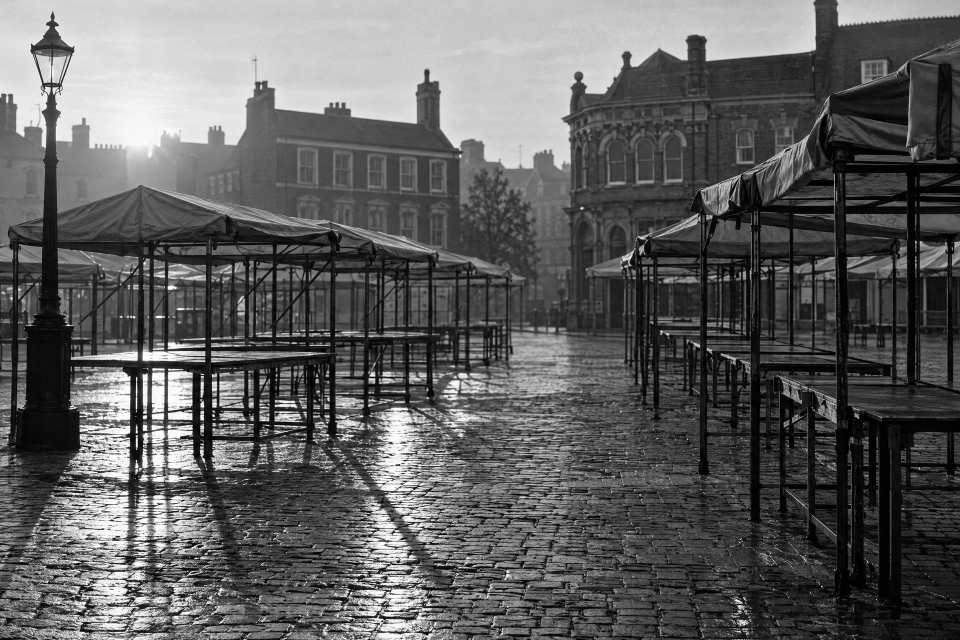 Empty market stall frames on a cobbled square at dawn