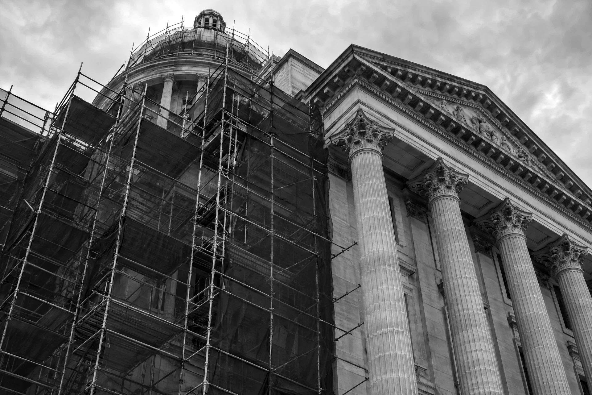 A neoclassical civic facade partly wrapped in scaffolding